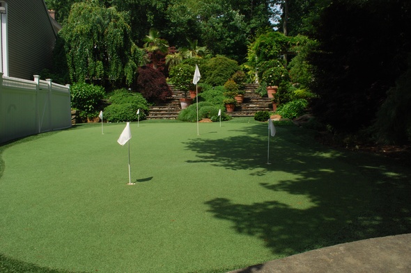 Edmonton Synthetic grass golf green with flags in a landscaped backyard